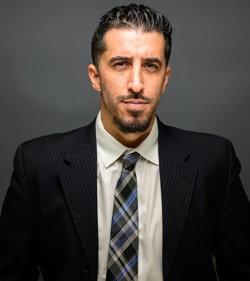 Jorge A. Abreu in a suit with striped tie, dark background, looking confident.