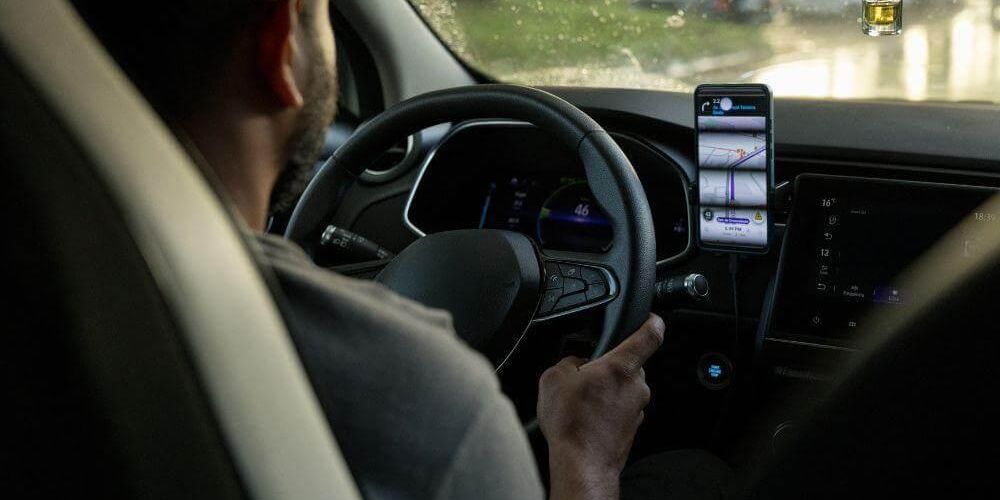Man driving car while holding cell phone