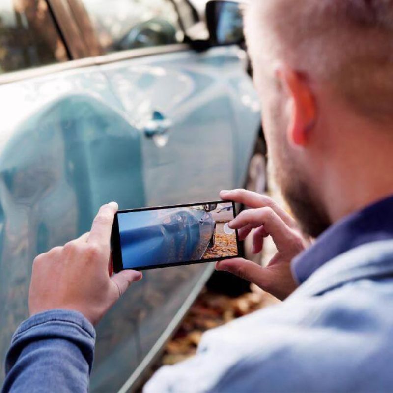 Man using cell phone to photograph car accident