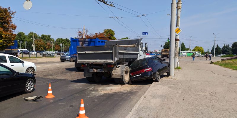 Truck and car collision at city intersection with traffic cones marking the scene.