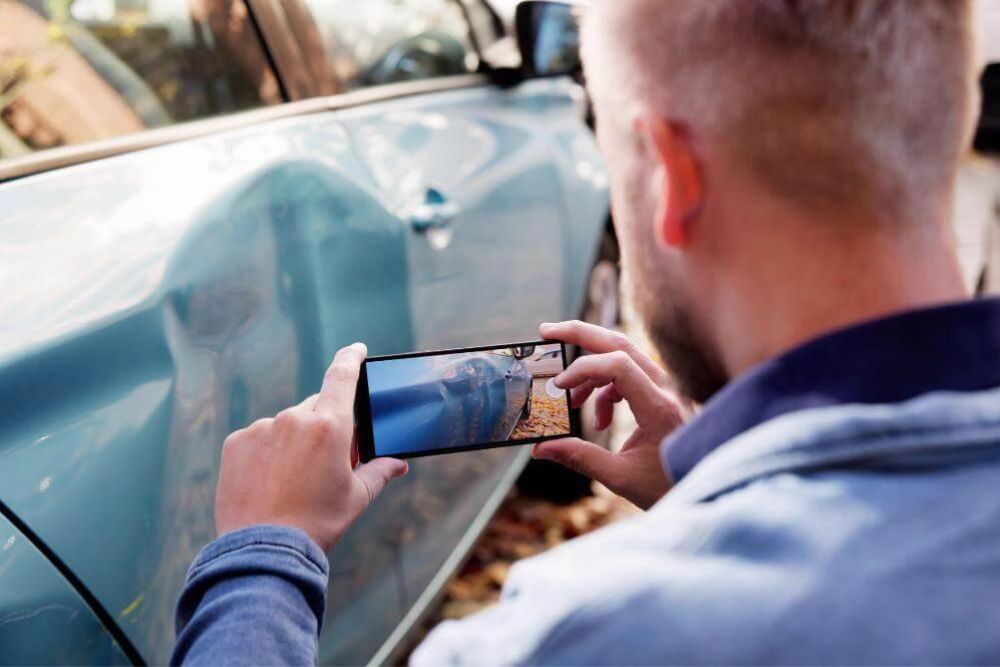 Man using cell phone to photograph car accident