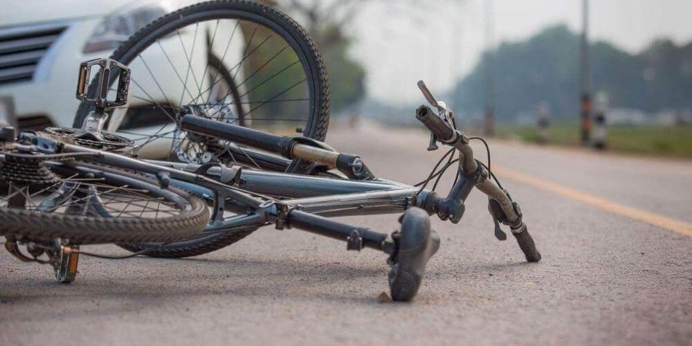Bicycle laying on the ground at side of road