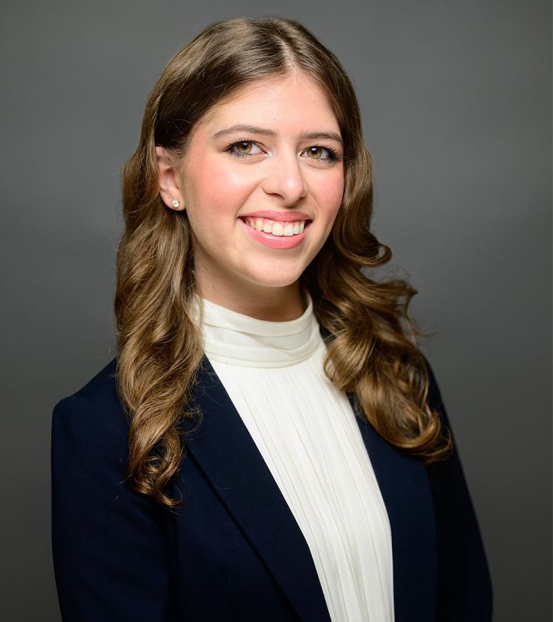Professional woman in business attire smiling against a neutral background.