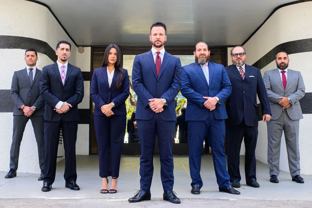 Business team in formal attire standing confidently outside modern building entrance.