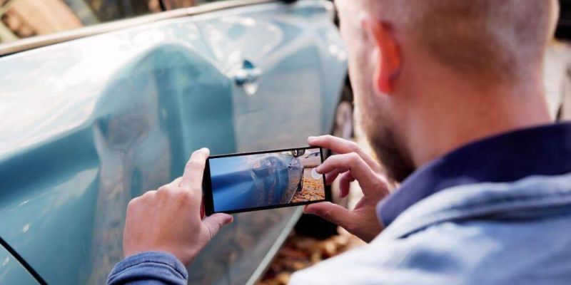 Man using cell phone to photograph car accident