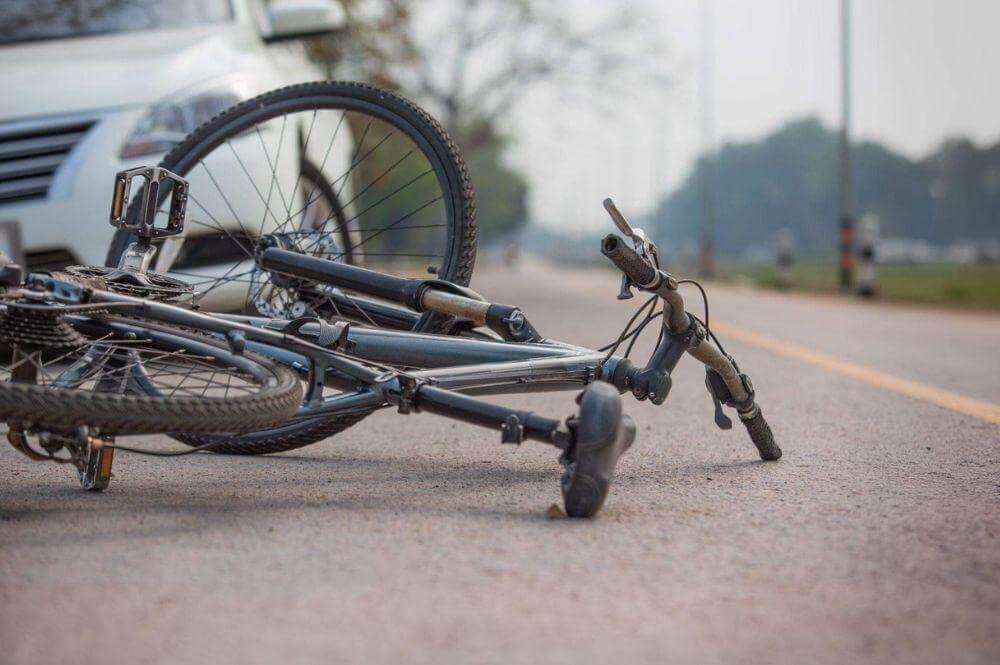 Bicycle laying on the ground at side of road