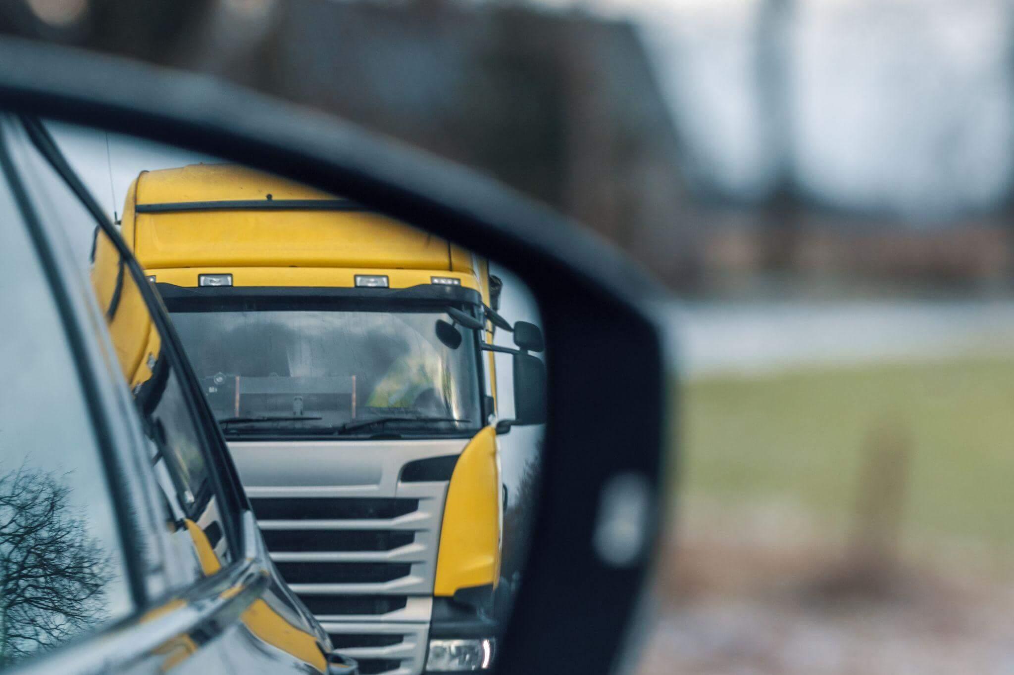 Yellow truck reflection in rear-view mirror