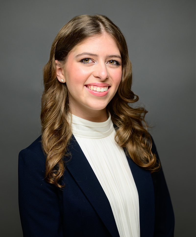 Professional woman in business attire smiling against a neutral background.
