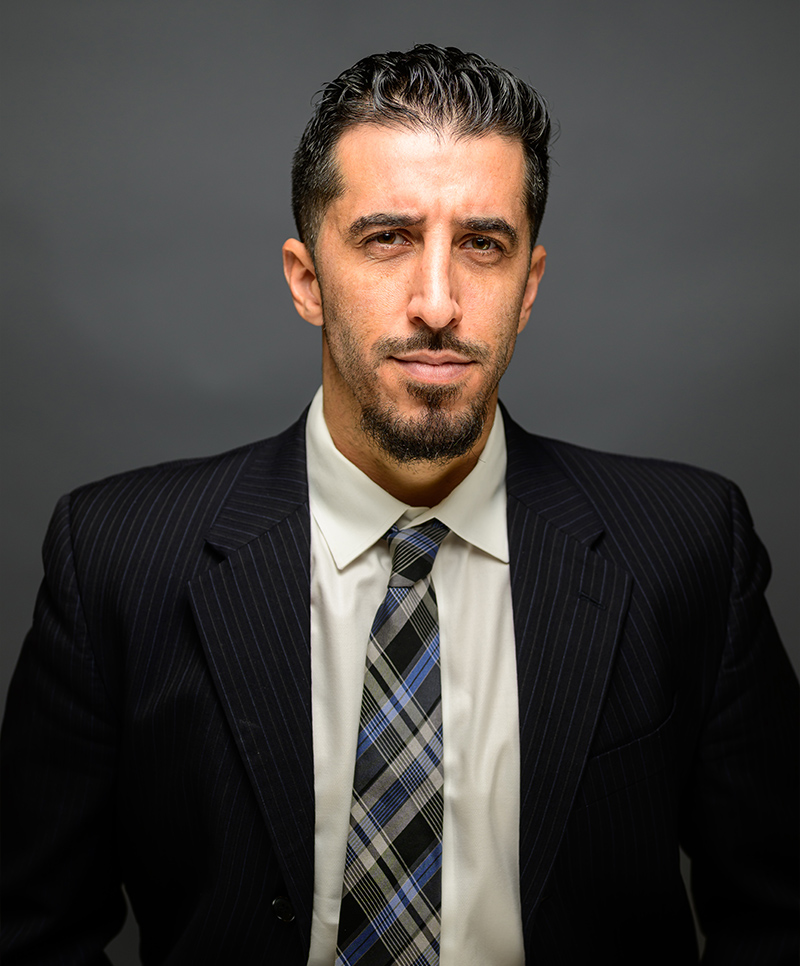 Jorge A. Abreu in a suit with striped tie, dark background, looking confident.