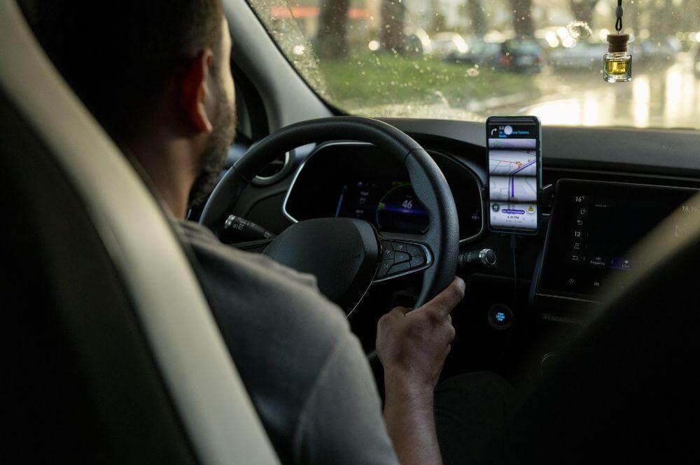 Man driving car while holding cell phone